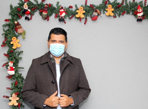 Latino man with protection mask and Christmas decoration, new normal covid-19 - Photo, Image