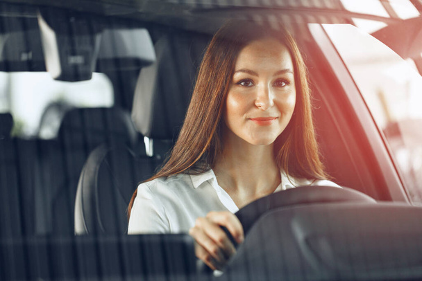 Happy woman driving a car and smiling - Zdjęcie, obraz