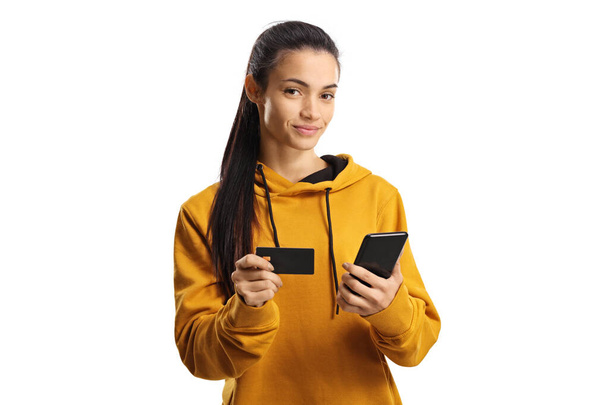 Young casual female paying with credit card and a mobile phone isolated on white background - Valokuva, kuva