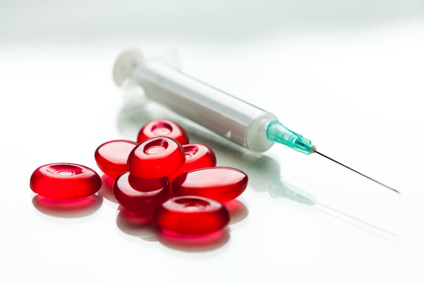 反射と白の背景に隔離された針で赤い丸薬と注射器の山,コロナウイルスCOVID-19ウイルス疾患治療&治療コンセプト,免疫系の防衛,ワクチン治療開発試験 - 写真・画像