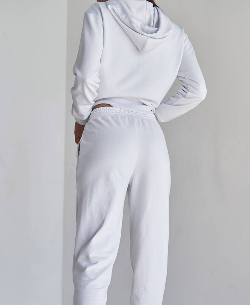 vrouw staat in witte broek van achteren. sportieve meisjes draagt strakke textiel broek - Foto, afbeelding