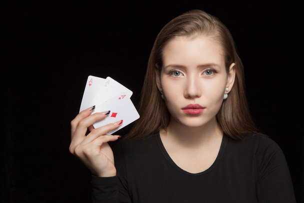 Beautiful blond woman showing a poker card on black background - Foto, imagen