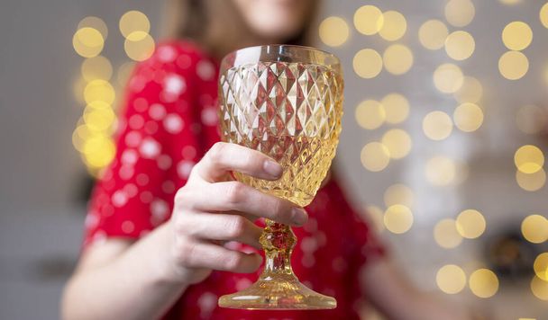 Woman at home decorated for christmas holding glass of wine and cheers close up. - 写真・画像
