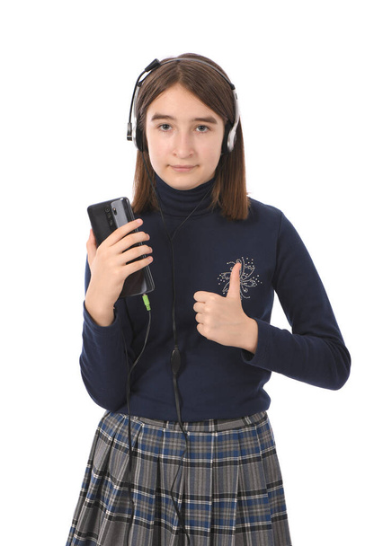 Ergenlik öncesi kız siyah akıllı telefondan müzik dinliyor. Beyaz arka planda izole edilmiş. Yüksek çözünürlüklü. Tam alan derinliği. - Fotoğraf, Görsel