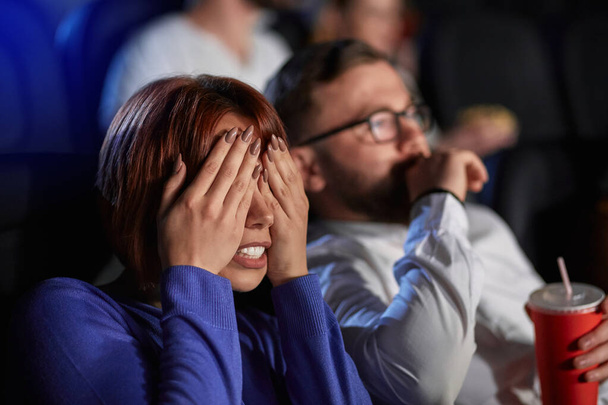 Caucasian couple watching horror movie in movie theater. - Foto, afbeelding