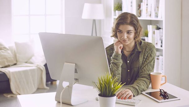 Молодая женщина, работающая с графическим планшетом в офисе
 - Фото, изображение