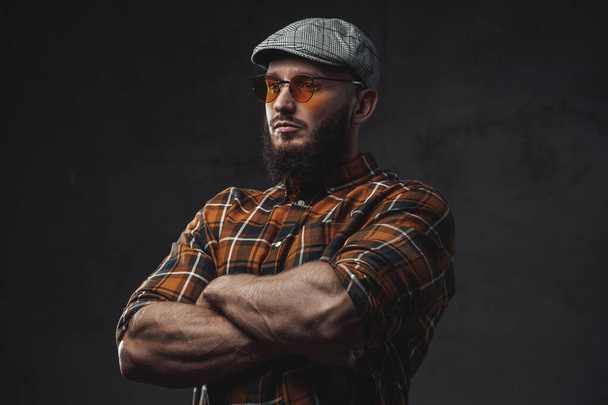 Elegante hombre hipster con gorra y gafas de sol en fondo oscuro - Foto, imagen