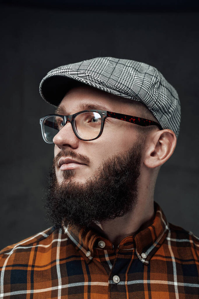 Stylischer Hipster mit Bart und Brille vor dunklem Hintergrund - Foto, Bild