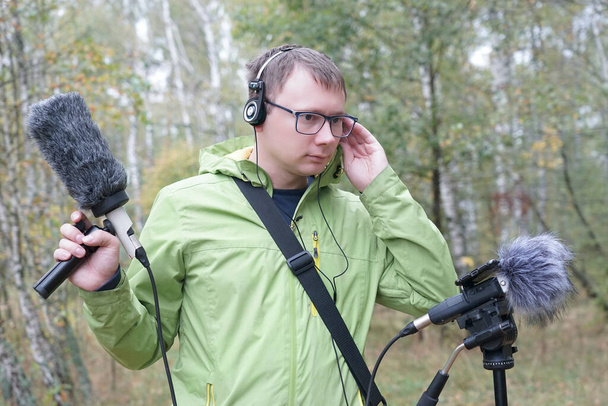 Chlápek s myerophne a sluchátky nahrává zvuky přírody. Nahrávání okolních zvuků - Fotografie, Obrázek