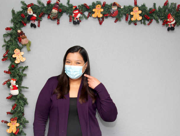 black hair latin woman with protection mask in christmas decoration, new normal covid-19 - Photo, Image
