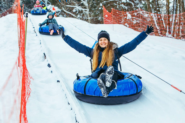 mulher sorridente no tubo de neve puxado para cima pela colina de inverno - Foto, Imagem