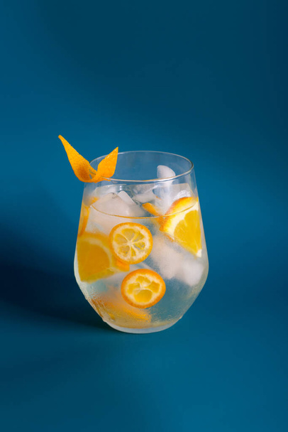 Orange lemonade with ice and slice of citrus in glass at blue minimal background with shadow. Concept of modern picture of menu - Valokuva, kuva