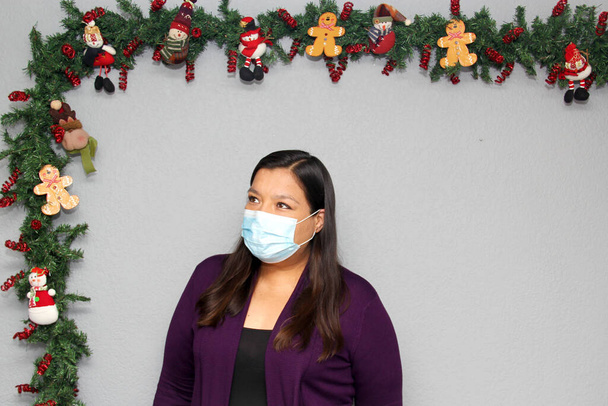 mujer latina de pelo negro con máscara de protección en la decoración de Navidad, nuevo covid-19 normal - Foto, Imagen