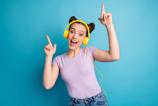 Photo of cheerful cool lady two buns good mood listen modern earphones popular song excited dj dancing fingers party wear casual purple t-shirt isolated blue color background - Photo, Image