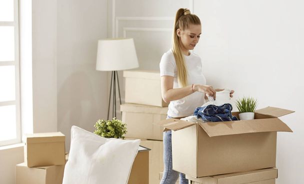 Girl parses things when moving to a new house - Zdjęcie, obraz