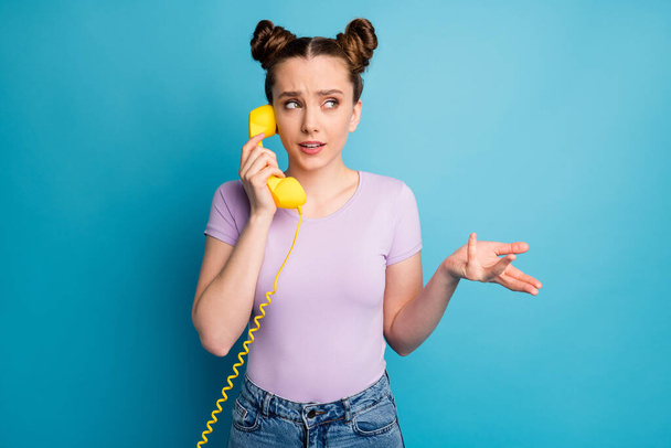 Photo of pretty lady two funny buns hold cable telephone handset speaking chatting friends explaining last gossips rumors wear casual purple t-shirt isolated blue color background - Fotografie, Obrázek