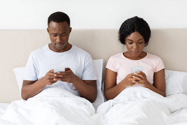 Homem e mulher sentados na cama e usando seus smartphones - Foto, Imagem
