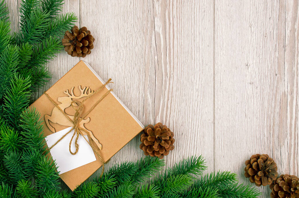 Πρωτοχρονιάτικη συσκευασία δώρου με ελάφι, κλαδί χριστουγεννιάτικο δέντρο σε ξύλινο φόντο. Banner με χώρο για κείμενο. ρουστίκ φόντο. Vintage σανιδωτό ξύλο με κλαδιά χριστουγεννιάτικων δέντρων.Επίπεδη lay. Άνω τελεία - Φωτογραφία, εικόνα
