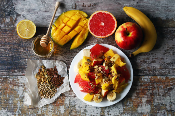 Φρέσκια ζουμερή φρουτοσαλάτα σε πιάτο με μάνγκο, γκρέιπφρουτ και σπόρους. Υγιεινή τροφή. Χορτοφαγική διατροφή. - Φωτογραφία, εικόνα