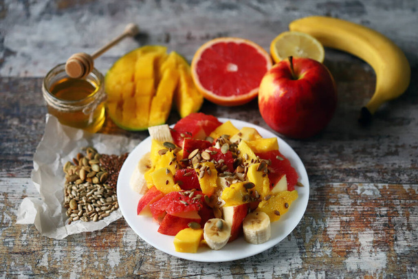 Čerstvý šťavnatý ovocný salát na talíři s mangem, grepem a semínky. Zdravé jídlo. Veganská strava. - Fotografie, Obrázek