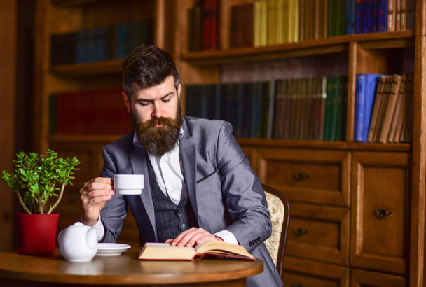 Literature, classic, library, afternoon tea concept. Mature man with thoughtful face enjoys reading. - Foto, Imagem