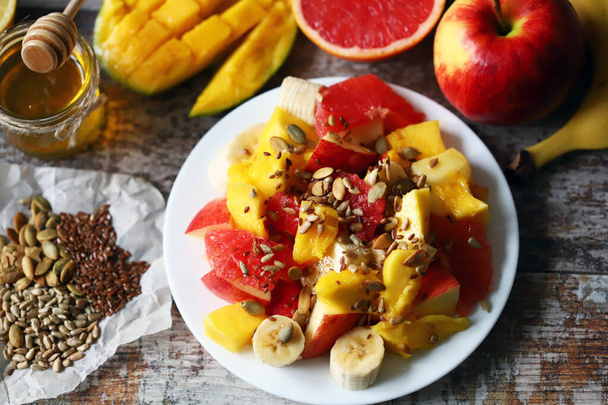 Świeża soczysta sałatka owocowa na talerzu z mango, grejpfrutem i nasionami. Zdrowe jedzenie. Dieta wegańska. - Zdjęcie, obraz