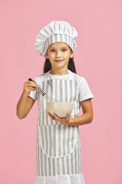 little girl mixing something with a whisk in bowl. - Foto, immagini