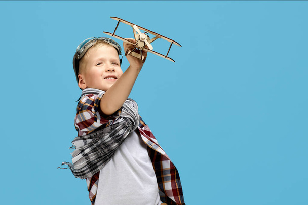 child boy in retro glasses playing with wooden toy airplane - Фото, изображение