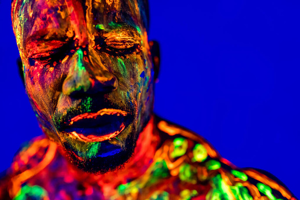 afro american man with UV body art posing in studio - Foto, Bild