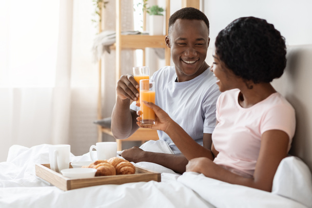 Feliz joven pareja negra desayunando en la cama en casa - Foto, Imagen