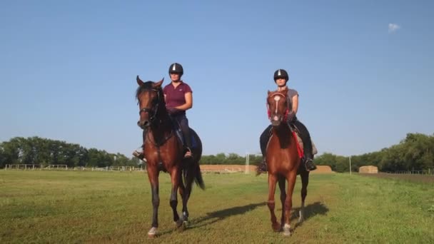 Dvě samice jezdí na koních podél venkovské dostihové dráhy - Záběry, video