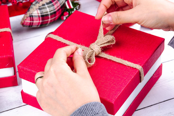 Zbliżenie rąk otwierających wstążkę czerwonego prezentu świątecznego - Zdjęcie, obraz
