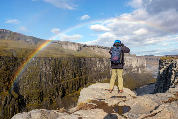 Bir fotoğrafçı Detifoss Şelalesi yakınlarındaki bir kanyonun üzerinde fotoğraf çekiyor, İzlanda 'nın altın yüzüğü.. - Fotoğraf, Görsel