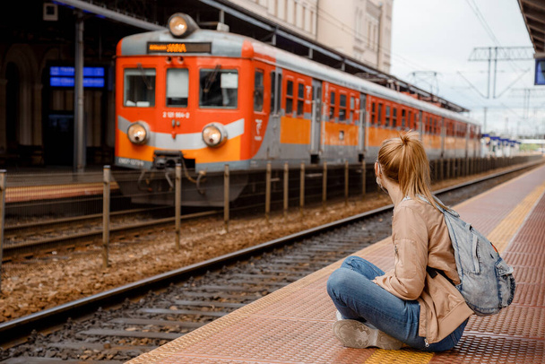 Junge Frau auf dem Bahnsteig wartet auf den Zug. Schöne Mädchen am Bahnhof. Anreise mit der Bahn. Bahnhof in Bydgoszcz. Polen. - Foto, Bild