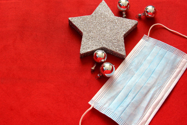 silver christmas star and spheres with protection mask on red background, christmas new normal covid-19 - Photo, Image