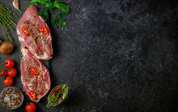 Fresh pork steaks with hot pepper, herbs and vegetables. Top view, copy space. Italian cuisine - Fotó, kép
