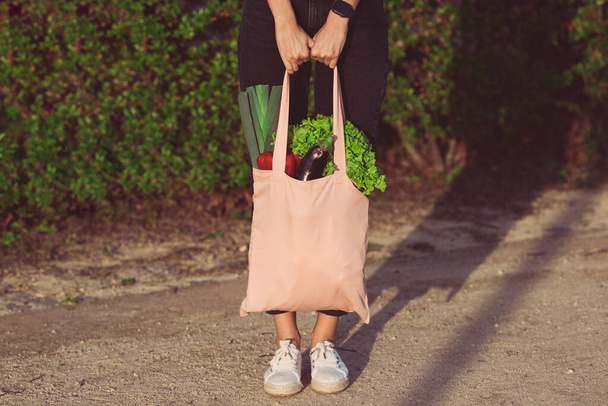 新鮮なバイオ野菜とピンクの再利用可能なエコバッグを持つ女性。植物性ビーガン食の買い物。健康食品きれいな食事。廃棄物ゼロプラスチックフリー - 写真・画像