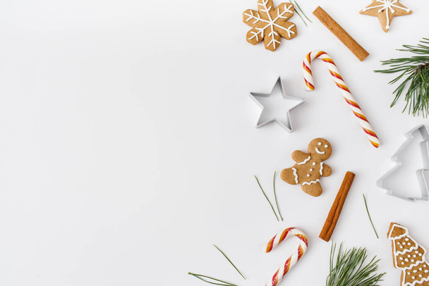 Christmas, winter, new year composition. Fir tree branches, cinnamon sticks, candies, gingerbread on white background. Flat lay, top view, copy space - Photo, image