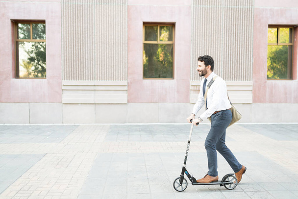 Homem adulto latino chegando ao seu trabalho em uma scooter. Homem de 30 anos sorrindo enquanto viajava para o trabalho  - Foto, Imagem