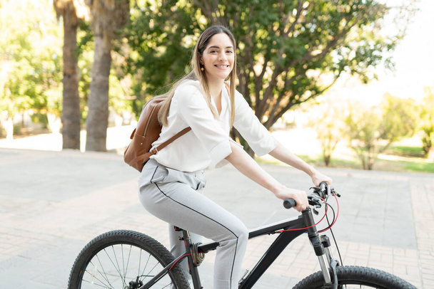 幸せなビジネスマン女性バックパックを自転車に乗って緑の公園を通って彼女の通勤上のオフィスから家へ - 写真・画像