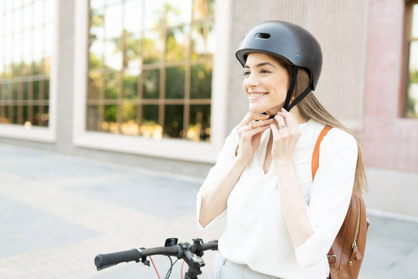 Blonďatá žena si nasazuje bezpečnostní přilbu, aby mohla použít své alternativní, ekologicky šetrné vozidlo k cestování ze své kanceláře domů  - Fotografie, Obrázek