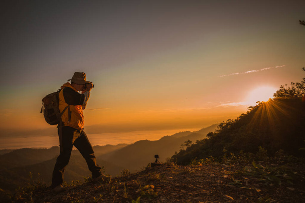 Νεαρός επαγγελματίας ταξιδιώτης άνθρωπος με κάμερα γυρίσματα υπαίθρια, φανταστικό ορεινό τοπίο - Φωτογραφία, εικόνα
