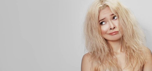 Bad hair day. Beautiful woman with messed up hair. Unhappy grimacing face. Blond bleaching hairstyle with problem brittle hair - Foto, Imagem