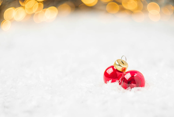 Punainen joulupallot makaa lumella taustalla joulukuusi ja hämärtynyt kultainen valot kopioi tilaa. Uudenvuoden juhlien valmistelu. - Valokuva, kuva