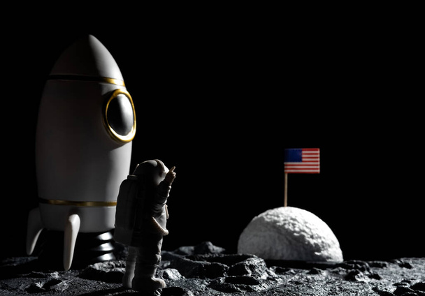 Astronot, kraterleri yatay bileşimlerde olan bir gezegende Amerikan bayrağıyla karşı karşıya. - Fotoğraf, Görsel