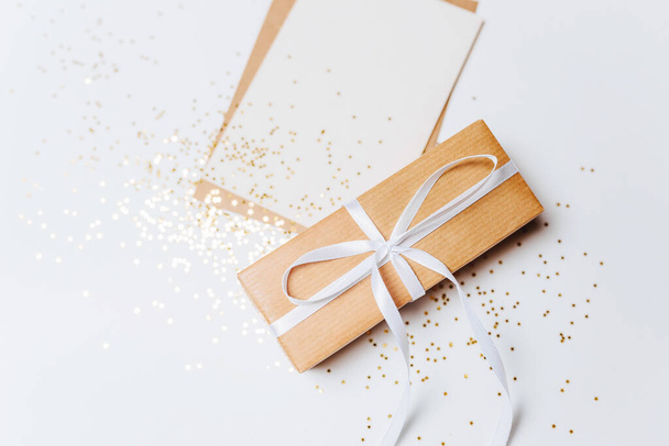 Gift and blank note with envelope, gold glitter stars on white background - Φωτογραφία, εικόνα