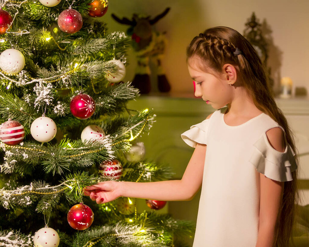 Girl in Stylish Dress Sitting on the Floor in Front of Christmas Tree. - Foto, Bild