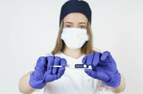 Medicine and health concept. Young woman doctor shows the temperature on the thermometer. Isolated over white background. - Фото, изображение