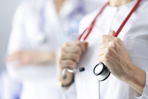 Doctor cardiologist holding red stethoscope in office of clinic closeup - Photo, Image
