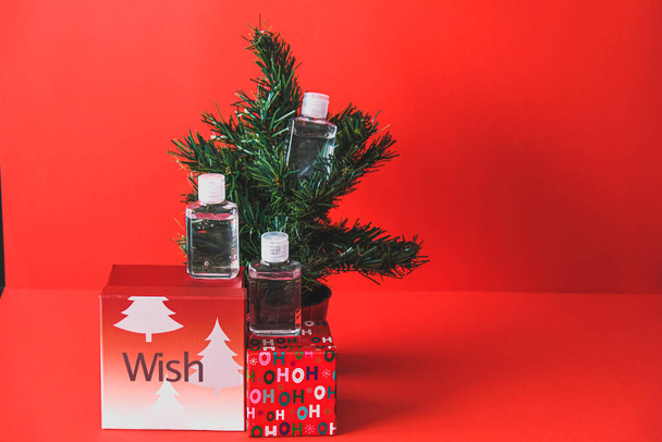 Χριστουγεννιάτικο δέντρο με απολυμαντικό χεριών και δώρα - Φωτογραφία, εικόνα